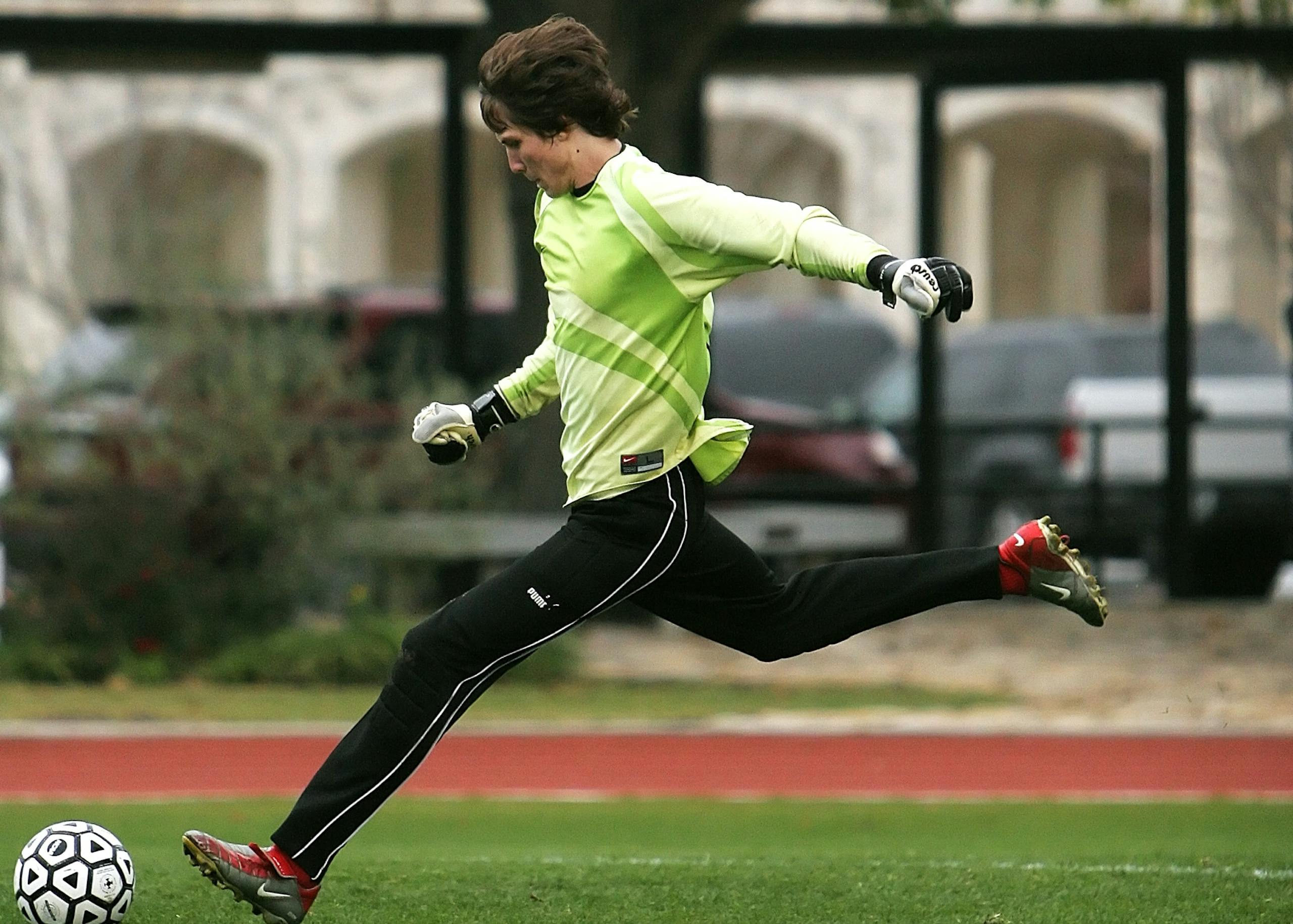 Man in Black Pants Playing Soccer during Daytime